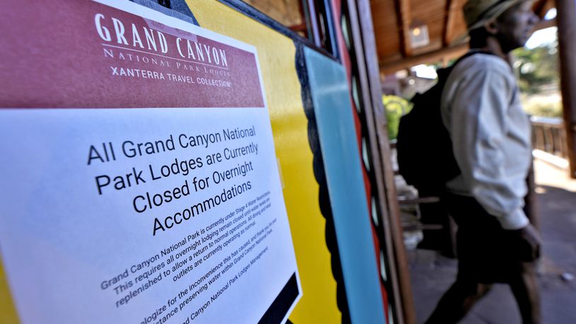 A sign denoting park lodge closures hangs on the door as a guest exits the Bright Angel Lodge, Thursday, Aug. 29, 2024, in Grand Canyon, Ariz. (AP Photo/Matt York)