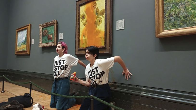 FILE - This photo provided by Just Stop Oil shows two protesters who have thrown tinned soup at Vincent Van Gogh's famous 1888 work Sunflowers at the National Gallery in London, Oct. 14, 2022. (Just Stop Oil via AP)