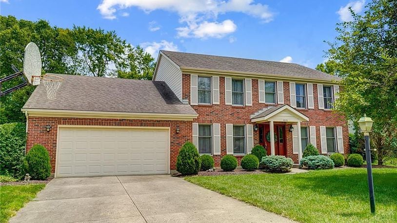 The front of the brick traditional two story has a two car attached garage with overhead storage and opener. The front porch has a covered portico.