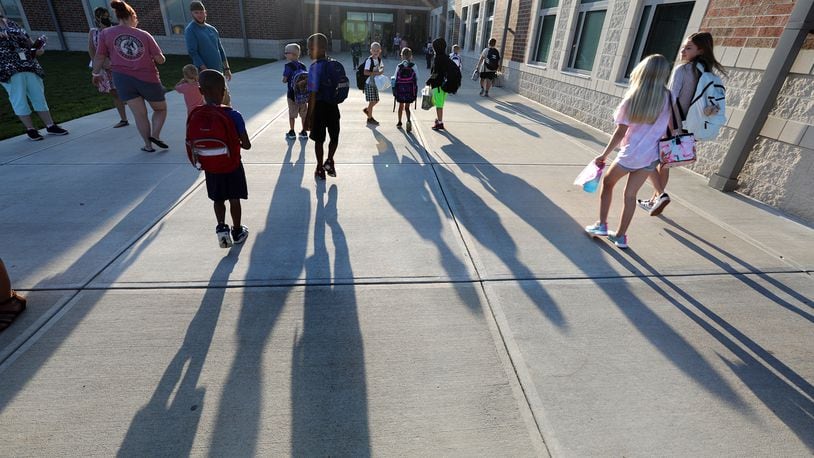 Urbana Elementary School students cast long shadows on the walkway as they walk into school for the first day Monday morning. BILL LACKEY/STAFF