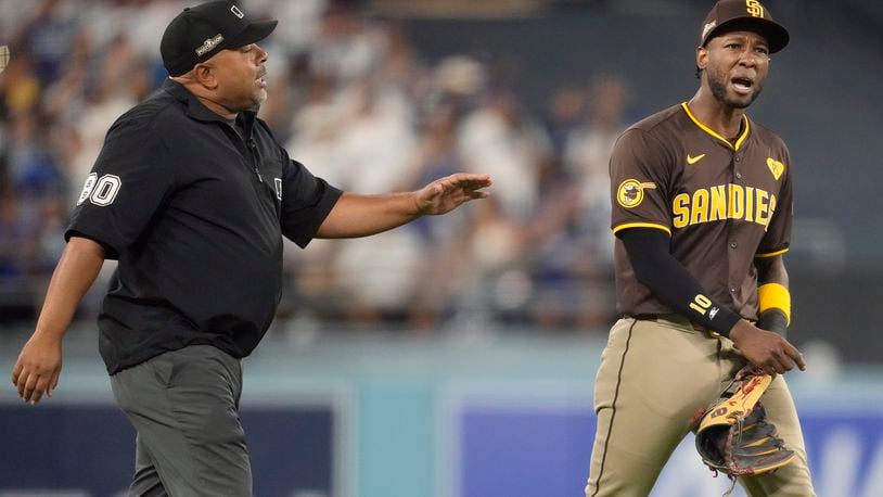 San Diego Padres left fielder Jurickson Profar, right, talks to umpire Adrian Johnson after items were thrown at Profar in the outfield during the seventh inning in Game 2 of a baseball NL Division Series against the Los Angeles Dodgers, Sunday, Oct. 6, 2024, in Los Angeles. (AP Photo/Ashley Landis)