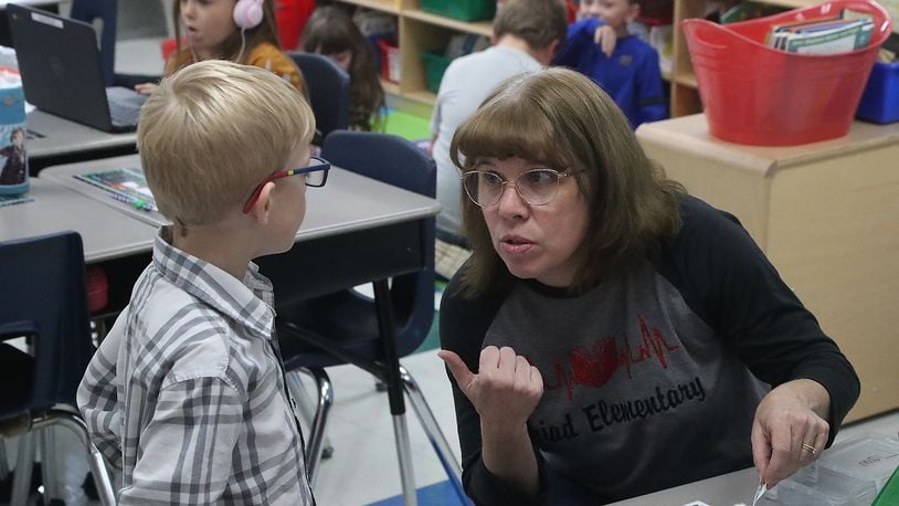 Schools in Clark and Champaign counties have reported an increase in COVID-19 cases from last week. Here, Diana Ferguson works with a student in her first grade class at Triad Elementary. BILL LACKEY/STAFF