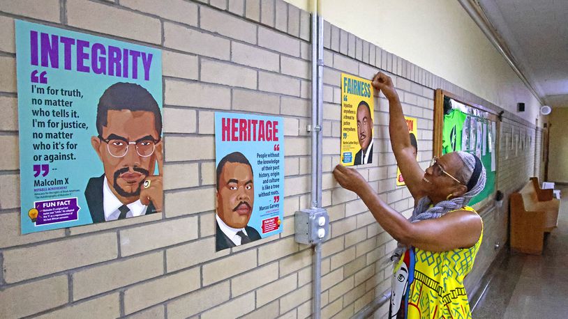 Jeannette Anderson, office manager at the Springfield Sports Academy, hangs pictures with messages on them in the hallway at the school Tuesday, July 30, 2024. The Springfield Sports Academy is getting ready to start their second year. BILL LACKEY/STAFF