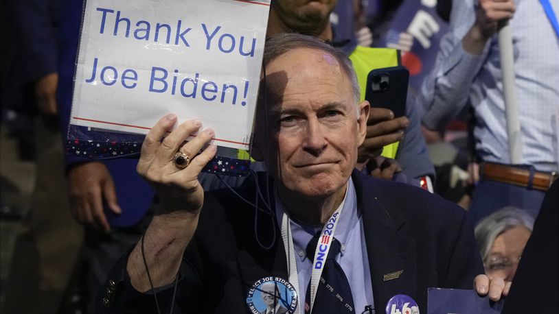 A delegate holds a sign as President Joe Biden speaks during the first day of Democratic National Convention, Monday, Aug. 19, 2024, in Chicago. (AP Photo/Jacquelyn Martin)