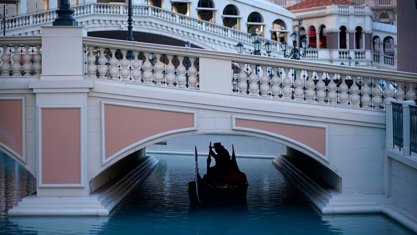 FILE - A gondolier steers his boat beneath a quiet pedestrian walkway at the Venetian hotel and casino in Las Vegas on Feb. 4, 2021. (AP Photo/John Locher, File)