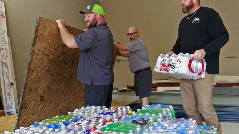 Casey Tingley, president of Ohio Hope Builders, left, Mark Houseman from Guardian Exteriors and Restoration, and Bryce White from Whites Family Fencing, unload supplies for the storm victims down south Tuesday, Oct. 1, 2024. BILL LACKEY/STAFF