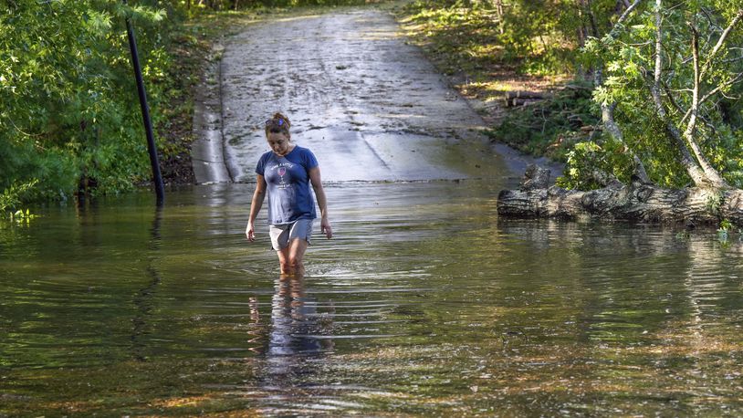 FILE - Teresa Elder walks through a flooded Sandy Cove Drive from Hurricane Helene, Sept. 27, 2024, in Morganton, N.C. (AP Photo/Kathy Kmonicek, File)