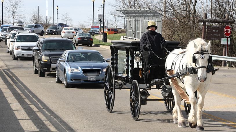 A long procession of cars slowly follows a horse-drawn hearse, carrying the body of Melvin Belle, 16, through the streets of Springfield to Ferncliff Cemetery Tuesday, March 29, 2022. Belle was shot and killed on South Yellow Springs Street this month. BILL LACKEY/STAFF