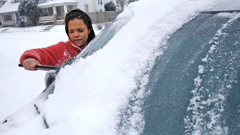 Brittany McNeal uses a broom to clean the snow off her car Friday, Jan. 19, 2024 along Cedar Street in Springfield. BILL LACKEY/STAFF