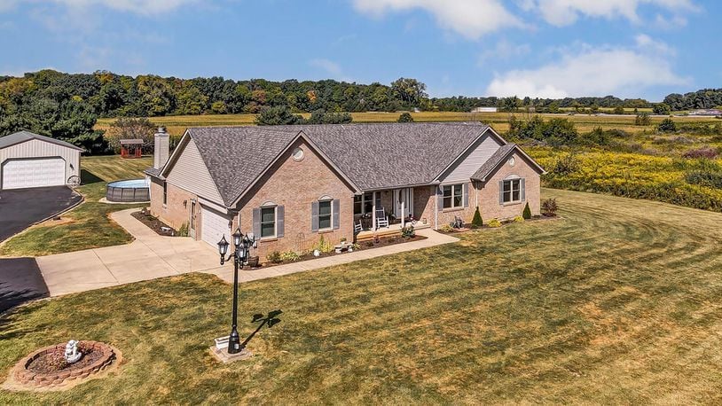 The front of the brick and siding ranch home has a covered front porch with pillars and professional landscaping touches.