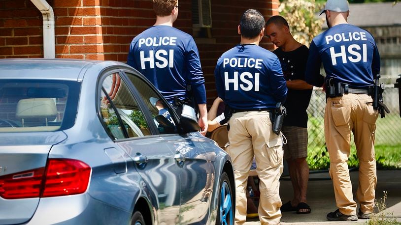 Homeland Security police talk to several people outside a home Friday, July 26, 2024 on Hoyle Pl. in Kettering. MARSHALL GORBY \STAFF