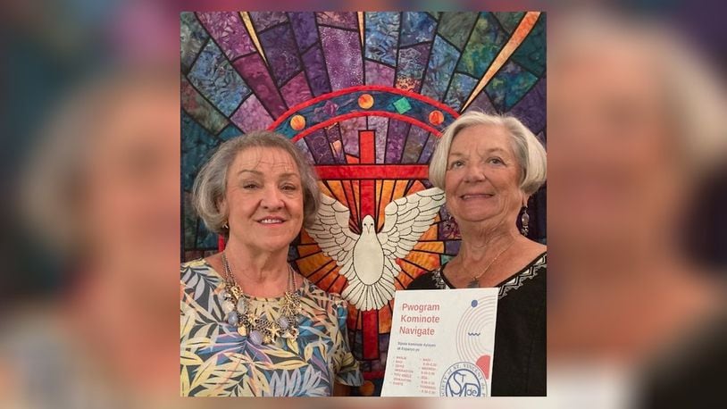 Nurse Connie Mitchell, right, holds a Creole language flier with Pastor Vicki Downing in the sanctuary of Springfield's Grace United Methodist Church. (Photo: 
 TOM STAFFORD)