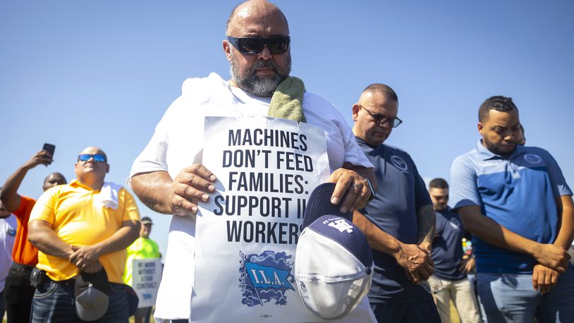 Longshoremen bow for a prayer during a strike at the Bayport Container Terminal on Tuesday, Oct. 1, 2024, in Houston. (AP Photo/Annie Mulligan)