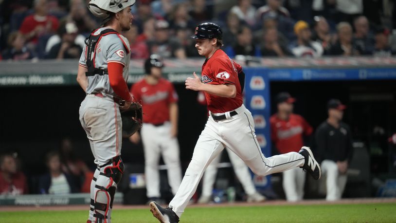 Cleveland Guardians' Kyle Manzardo, right, runs home past Cincinnati Reds catcher Tyler Stephenson, left, to score on a sacrifice fly hit by Josh Naylor in the seventh inning of a baseball game in Cleveland, Tuesday, Sept. 24, 2024. (AP Photo/Sue Ogrocki)