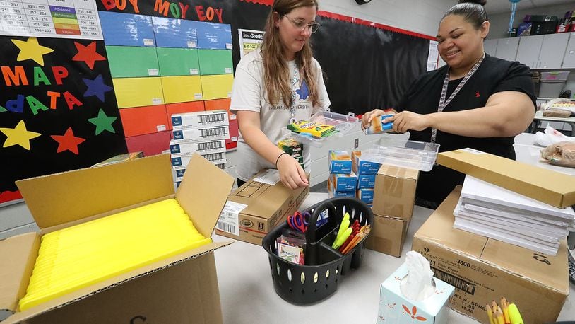 The Springfield City School District will provide school supplies to students in kindergarten through eighth grades for the fourth year in a row. In this file photo, Fulton Elementary School teacher's Mikyla Timmerman, left, and Kathleen Haley put school supplies into plastic boxes for each student as they prepared for school to start. FILE/BILL LACKEY/STAFF