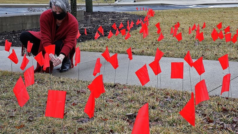Lori Common, assitant to the vice president marketing diversity community impact at Clark State College, sets up one of the dozens of red flags on the lawn at the Springfield campus Tuesday. The goal of the Red Flag campaign is to keep safe and aware of domestic violence. BILL LACKEY/STAFF