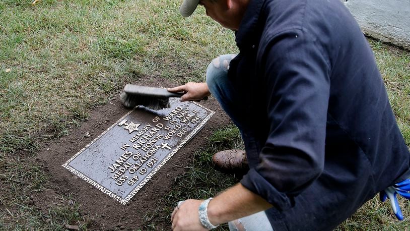 Rob Kelly, a member of the Ferncliff Cemetery grounds crew, brushes off the new grave marker for Medal of Honor winner and Clark County native James Richard Ward after placing it in the World War II veterans section at Ferncliff Wednesday, July 10, 2024. The remains of Ward, who was killed on the USS Oklahoma at Pearl Harbor, were recently recovered and identified. His family asked for him to be buried at Arlington Cemetery in Washington D.C. and according to military rules, a veteran can only have one military grave marker and the marker that was placed at Ferncliff was removed. The cemetery recently had another marker made and today it was placed where the old marker was located. BILL LACKEY/STAFF