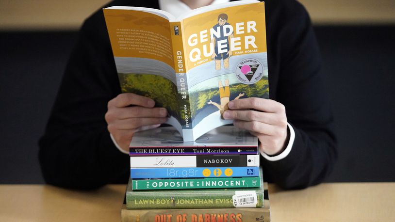 FILE - Amanda Darrow, director of youth, family and education programs at the Utah Pride Center, poses with books that have been the subject of complaints from parents, including "Gender Queer" by Meir Kobabe, on Dec. 16, 2021, in Salt Lake City. (AP Photo/Rick Bowmer, File)