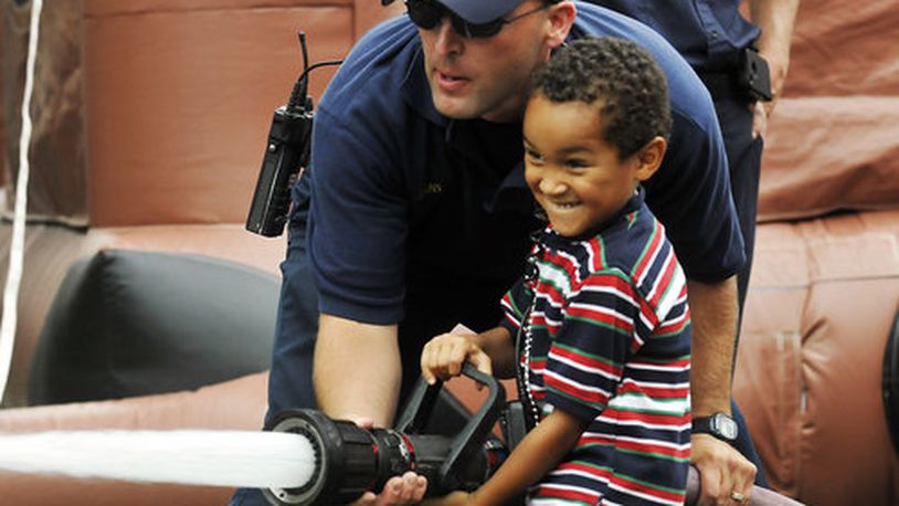 Devonte Williams, 5, grins as he opens up a fire hose with a little help from Springfield firefighter Clayton Atkins Saturday, August 20 during the Summer Sky festival for kids sponsored by Family & Children Services of Clark County.