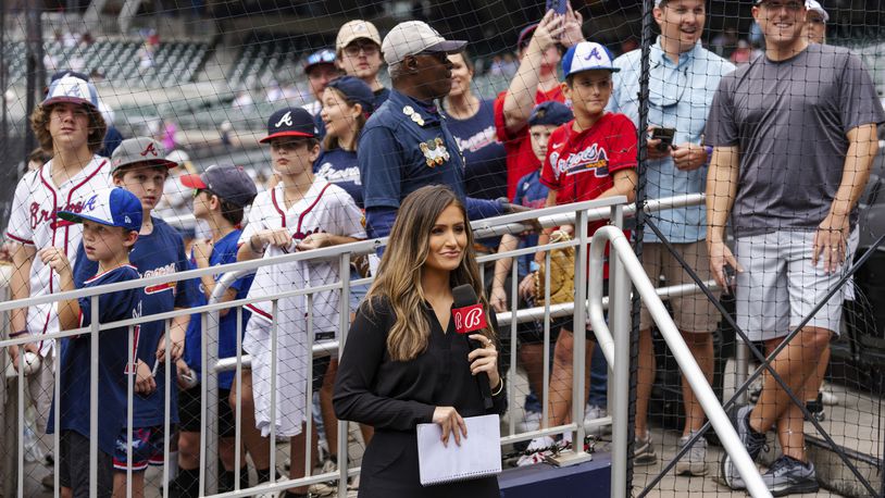 Bally reporter, Hanna Yates, broadcasts her pregame with fans standing behind her waiting for autographs before the start of a baseball game between the New York Mets and the Atlanta Braves, Monday, Sept. 30, 2024, in Atlanta. (AP Photo/Jason Allen)