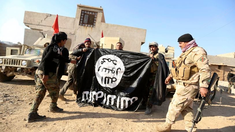 FILE - Iraqi Army soldiers celebrate as they hold a flag of the Islamic State group they captured during a military operation to regain control of a village outside Mosul, Iraq, Nov. 29, 2016. Ten years after the Islamic State group declared its caliphate in large parts of Iraq and Syria, the extremists now control no land, have lost many prominent founding leaders and are mostly away from the world news headlines. (AP Photo/Hadi Mizban, File)
