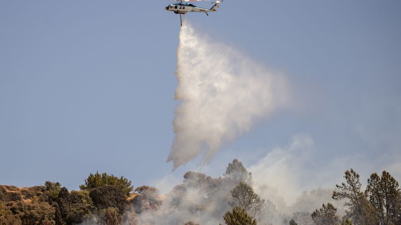 A Pacific Gas and Electric Company (PG&E) firefighting helicopter releases water over a hot spot while battling the Thompson Fire, in Oroville, Calif., Wednesday, July 3, 2024. (Stephen Lam/San Francisco Chronicle via AP)