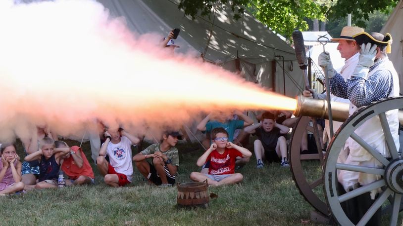 Children watch and cover their ears as the Mad River Light Artillery unit fires their cannon Friday, Aug. 30, 2024 during education day at the 42nd annual Fair at New Boston just outside Springfield. BILL LACKEY / STAFF