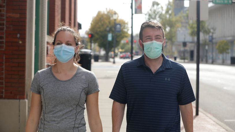 A couple wears masks as they walk along Fountain Avenue in Springfield Friday. BILL LACKEY/STAFF