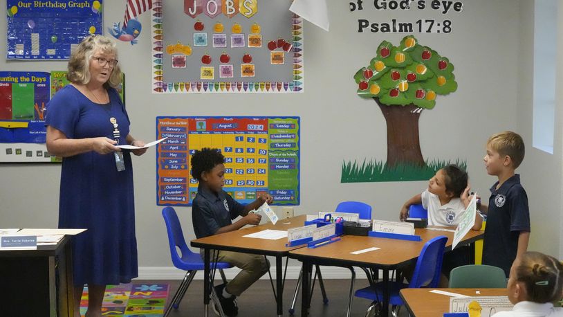 Kindergarten teacher Terrie Osborne helps students in her class at the Winter Garden Christian Academy Thursday, Aug. 29, 2024, in Winter Garden, Fla. (AP Photo/John Raoux)