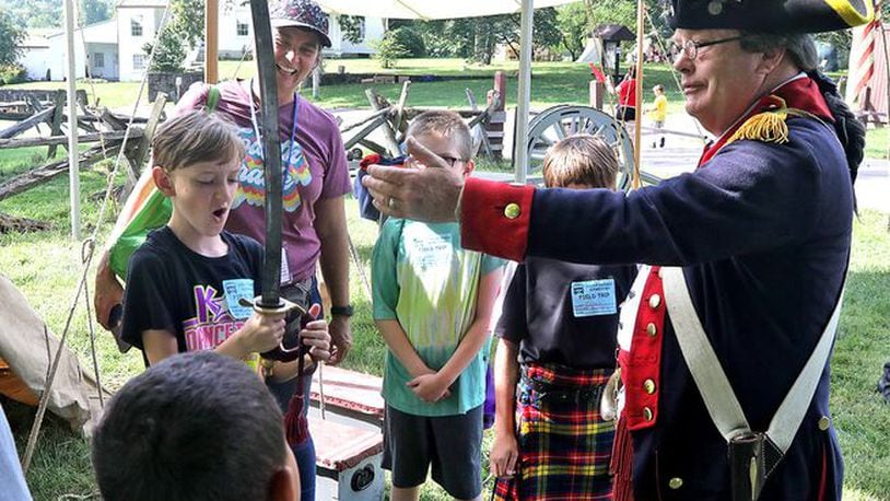 Dale Hawley explains the cannon to school children on Education Day. (BILL LACKEY)