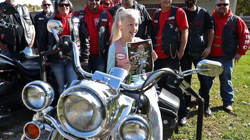 The youngest member of the Highway Hikers Motorcycle Club, Laila Vose, 8, holds a poster for the Highway Hikers Motorcycle Club's 2020 Toy Run, which takes place on October 18. BILL LACKEY/STAFF