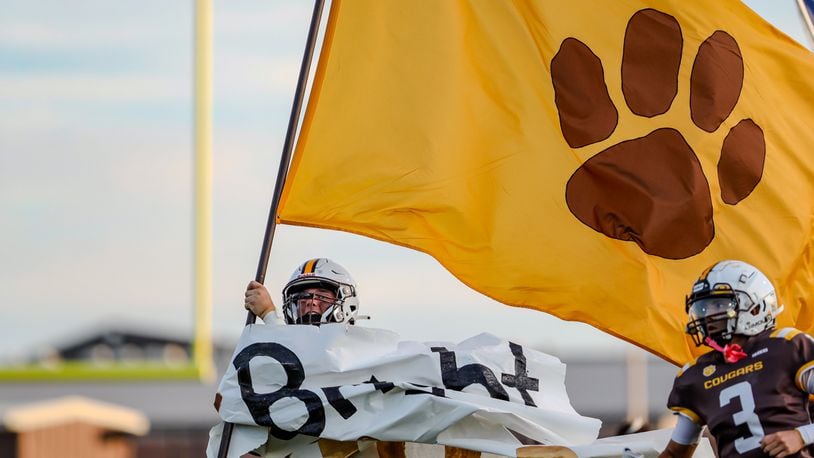 A Kenton Ridge High School football player carries their flag onto the field during their game against Northwestern earlier this season. CONTRIBUTED PHOTO BY MICHAEL COOPER