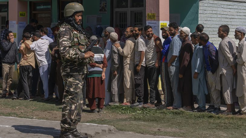 An Indian paramilitary soldier stands guard as people queue up at a polling booth to cast their vote in Bellow, south of Srinagar, Indian controlled Kashmir, Wednesday, Sept. 18, 2024. (AP Photo/Dar Yasin)