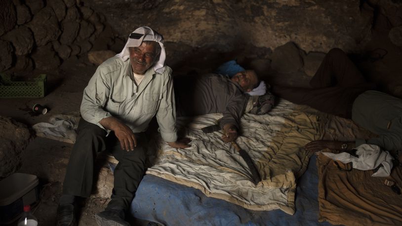 Palestinians Ribhi Ahmad Battat, left, and Issa Ahmad Battat, residents of the West Bank village of Khirbet Zanuta, take shelter from the midday sun in a cave Tuesday, Aug. 27, 2024. Ten months after settlers threatened to kill them if they didn't leave their village, some Palestinian residents are finally home, under a rare court order. (AP Photo/Maya Alleruzzo)