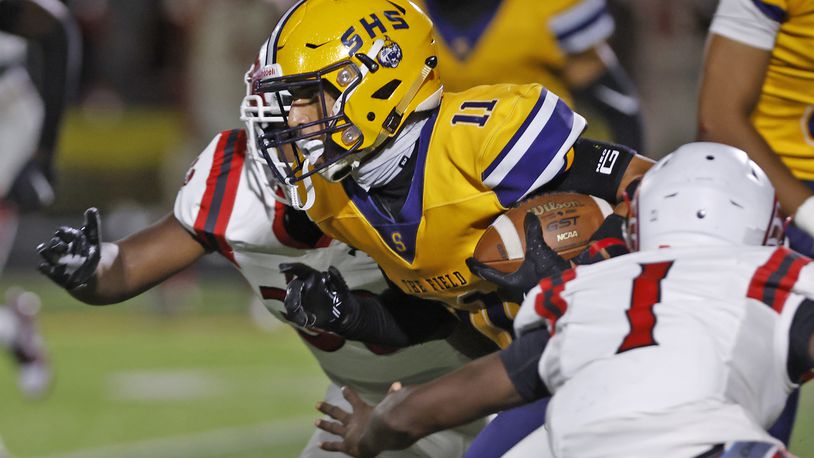 Springfield's Jamil Miller breaks through the Trotwood defensive line as he carries the ball. BILL LACKEY/STAFF