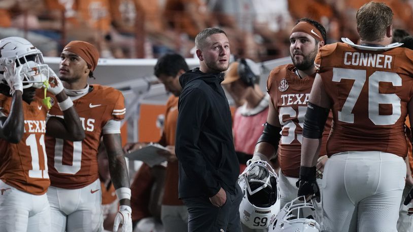 Texas quarterback Quinn Ewers, center, stands on the sidelines in street cloths after he was injured during the second half of an NCAA college football game against UTSA in Austin, Texas, Saturday, Sept. 14, 2024. (AP Photo/Eric Gay)