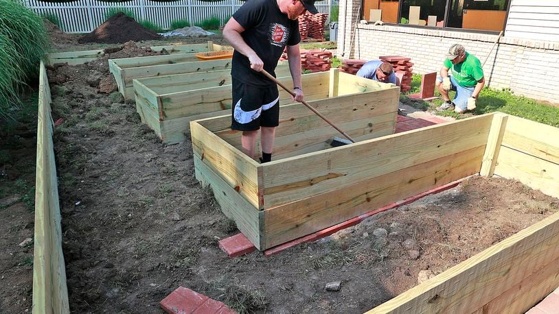 Members of the Clark County Senior Citizens Task Force work on a new handicapped accessible raised garden with paved walkways in the courtyard of the Good Shepherd Village Nursing Center. Ryan Ray, left, Alex Flora, center, and Larry Richards placing pavers around the garden Wednesday, July 12, 2023 that will allow the residents to grow flowers and vegetables. BILL LACKEY/STAFF