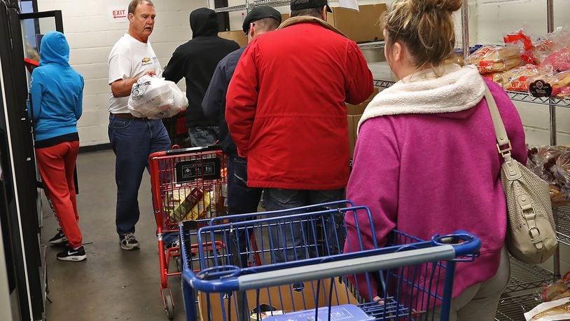 Nick Kneisley, a volunteer at the Second Harvest Food Bank, helps people in the food pantry Thursday, Nov. 29, 2018. BILL LACKEY/STAFF