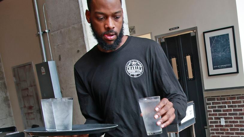 Demetrius Jones, a waiter at Charlo's Provisions & Eatery in downtown Springfield, delivers drinks to a table Wednesday, August 7, 2024. BILL LACKEY/STAFF