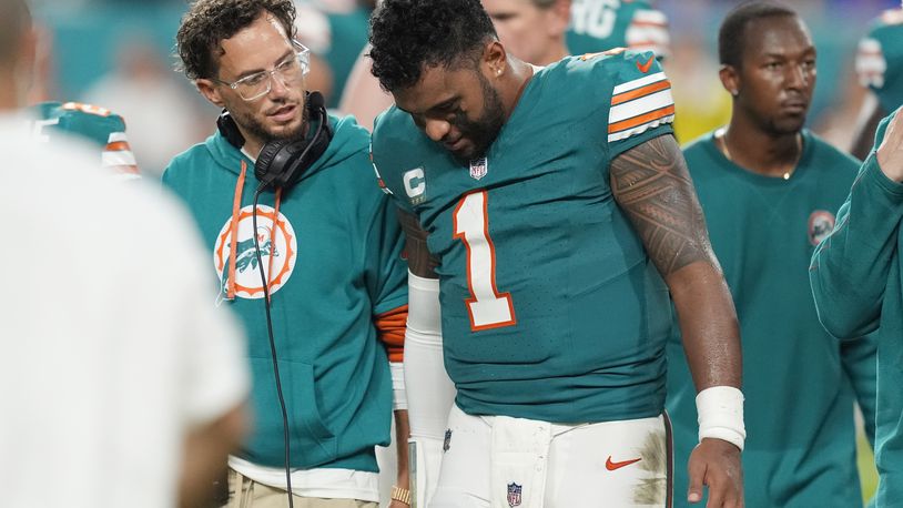 Miami Dolphins head coach Mike McDaniel talks to quarterback Tua Tagovailoa (1) as he leaves the game after suffering a concussion during the second half of an NFL football game against the Buffalo Bills, Thursday, Sept. 12, 2024, in Miami Gardens, Fla. (AP Photo/Rebecca Blackwell)