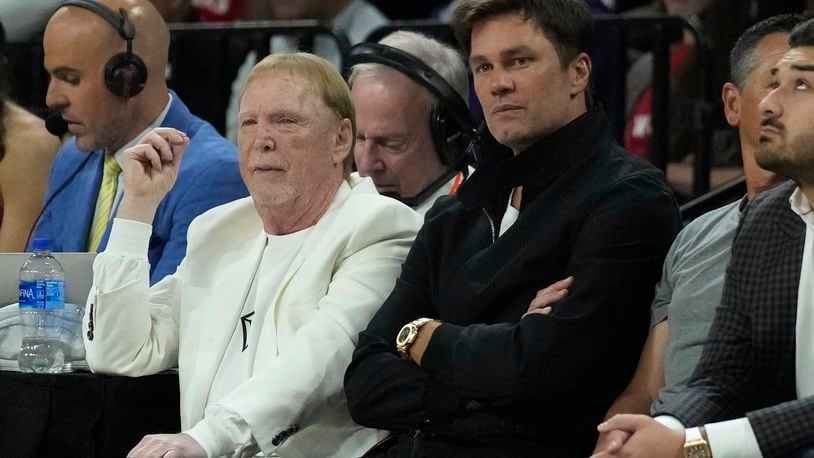 FILE - Mark Davis, left, owner of the Las Vegas Aces and Las Vegas Raiders, sits beside former football player Tom Brady during the first half in Game 1 of a WNBA basketball final playoff series between the Aces and New York Liberty, Sunday, Oct. 8, 2023, in Las Vegas. Magic Johnson’s love of basketball a decade ago motivated him to save the Los Angeles Sparks from folding and also put him on the forefront of what is now a growing WNBA trend. Tom Brady did the same with the Las Vegas Aces. (AP Photo/John Locher, File)