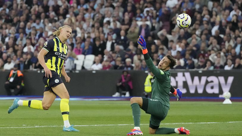 Manchester City's Erling Haaland, left, scores his side's third goal during the English Premier League soccer match between West Ham United and Manchester City at the London Stadium in London, England, Saturday, Aug. 31, 2024. (AP Photo/Frank Augstein)