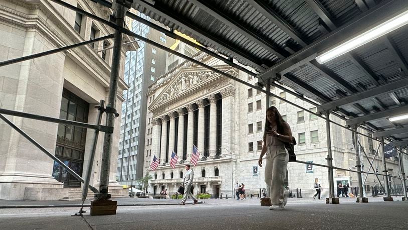 People pass the New York Stock Exchange, at rear, on Tuesday, Aug. 27, 2024, in New York. (AP Photo/Peter Morgan)