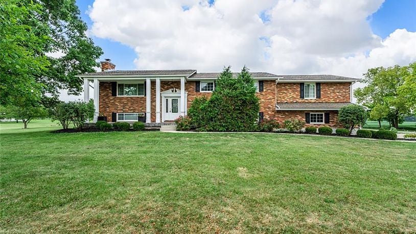 The front of the brick bi-level has a covered front porch with pillars and a concrete walk that leads to the driveway and two car attached side entry garage.