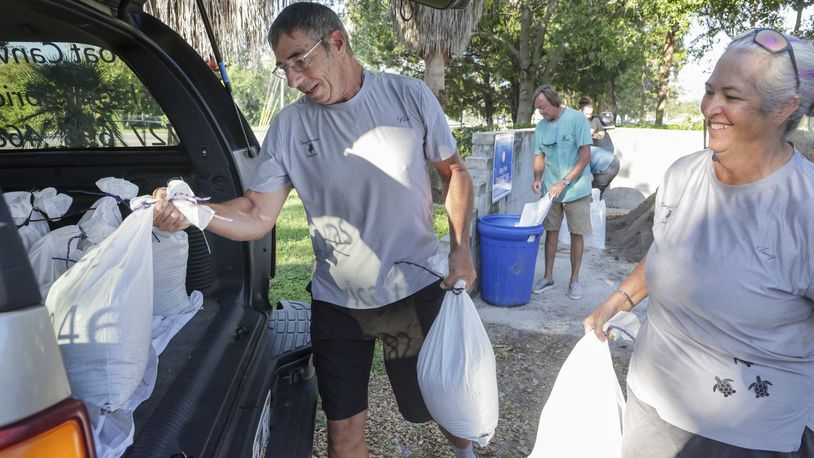 Karl Bohlmann, left, and Tangi Bohlmann, of Tarpon Springs, collect sandbags at a public site while residents prepare their homes for potential flooding, Tuesday, Sep 24, 2024, in Tarpon Springs, Fla., as the Tropical Storm Helene approaches. (Douglas R. Clifford/Tampa Bay Times via AP)