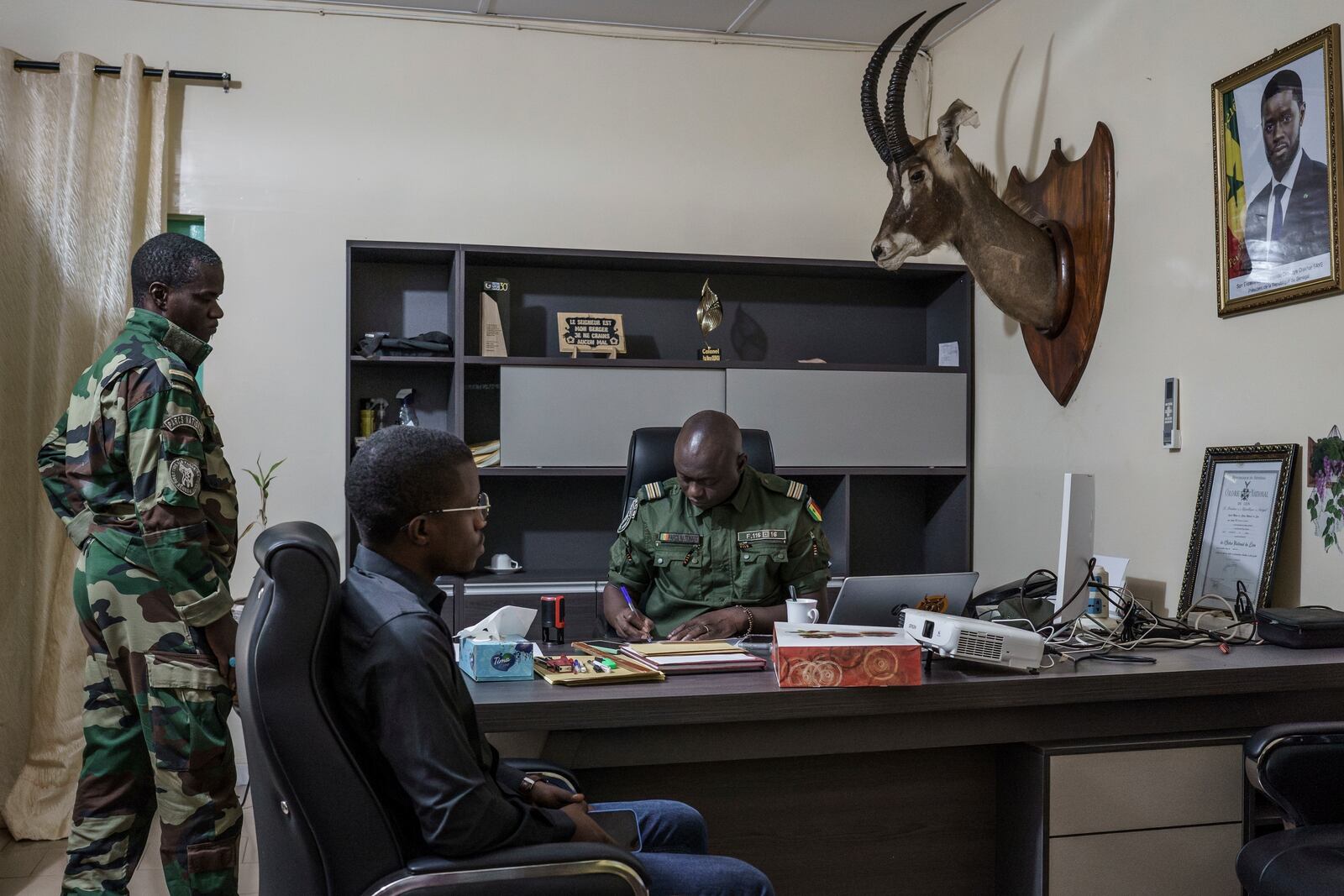 Paul Diedhiou, right, a colonel with Senegal's Direction of National Parks, works in his office at the DPN headquarters in Tambacounda, Senegal on Monday, Jan. 13, 2025. (AP Photo/Annika Hammerschlag)