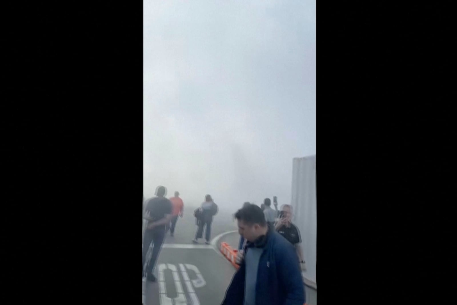 In this image taken from video provided by Justus Rainey, passengers move away from a plane as smoke surrounded the aircraft, in Denver, Thursday, March 13, 2025. (Justus Rainey via AP)