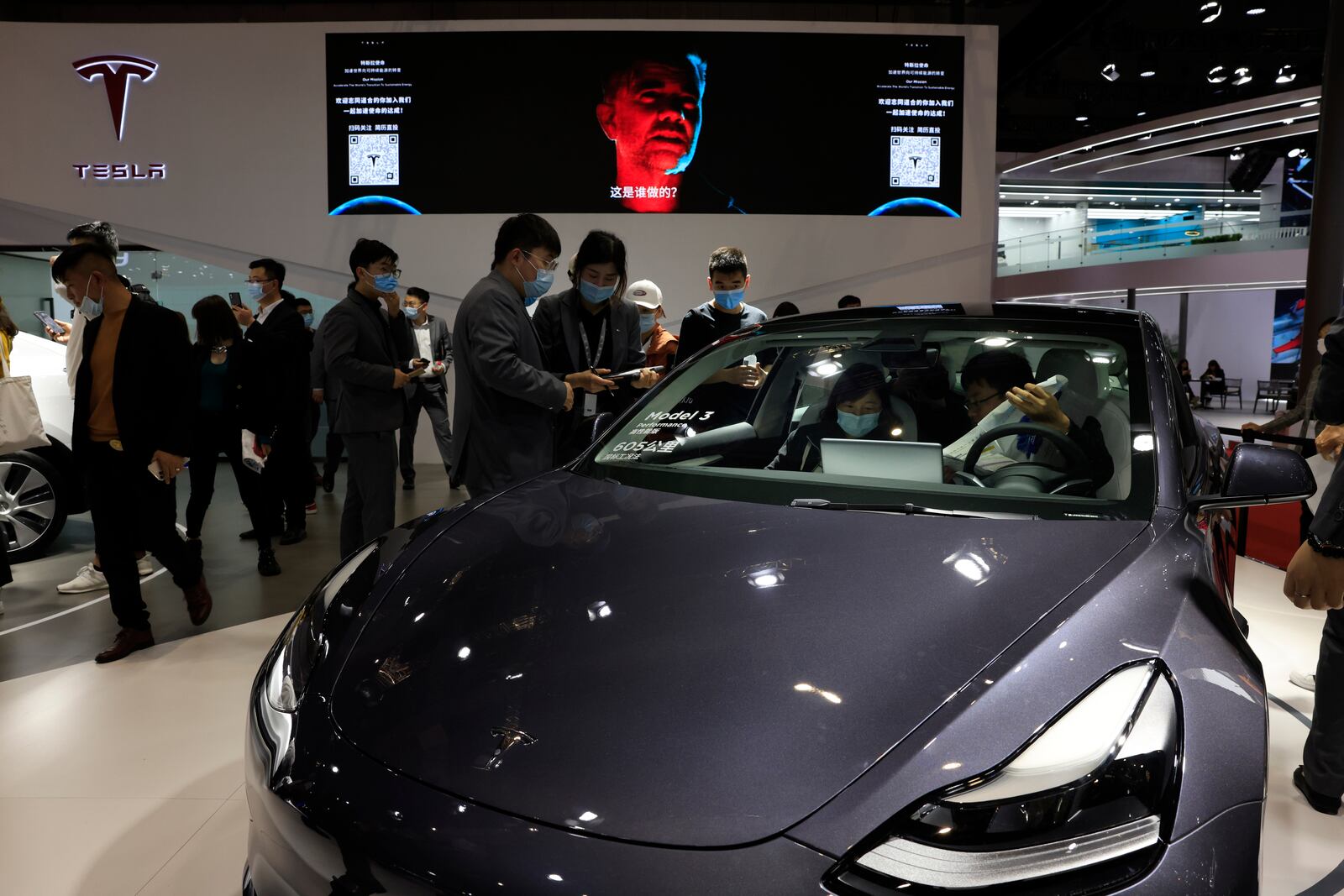 Visitors look at a Tesla Model 3 during the Shanghai Auto Show in Shanghai on Wednesday, April 21, 2021.  (AP Photo/Ng Han Guan)