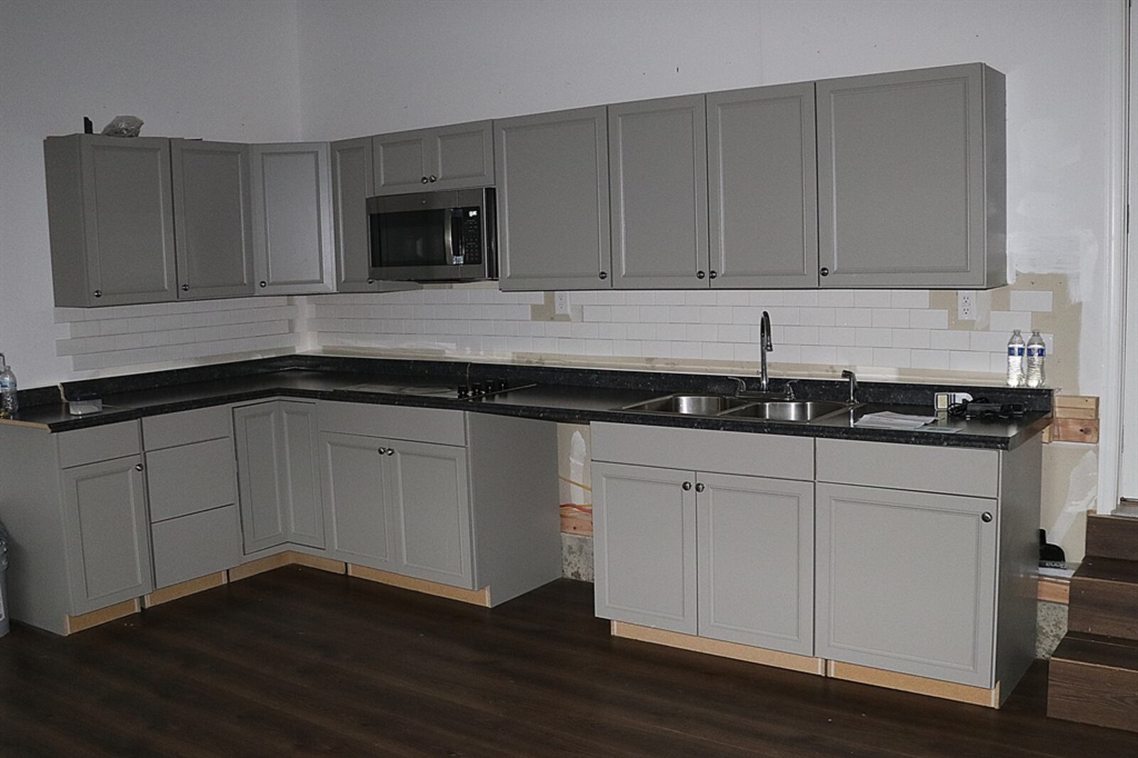 Along the back wall of the garage is a set of cabinets with a stainless-steel sink, microwave and appliance nook. 