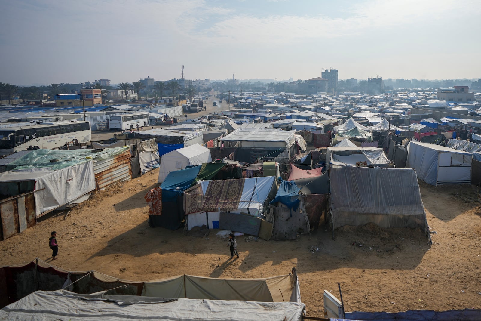 Palestinian children play among the tents at a camp for displaced Palestinians in Deir al-Balah, central Gaza Strip, Thursday Jan. 16, 2025. (AP Photo/Abdel Kareem Hana)